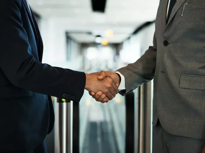 Two business professionals in suits shaking hands, representing successful local partnerships and trusted services